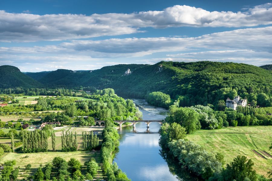 fotografía de río atraveesando la campiña con un castillo a la derecha fotografía de río atraveesando la campiña con un castillo a la derecha