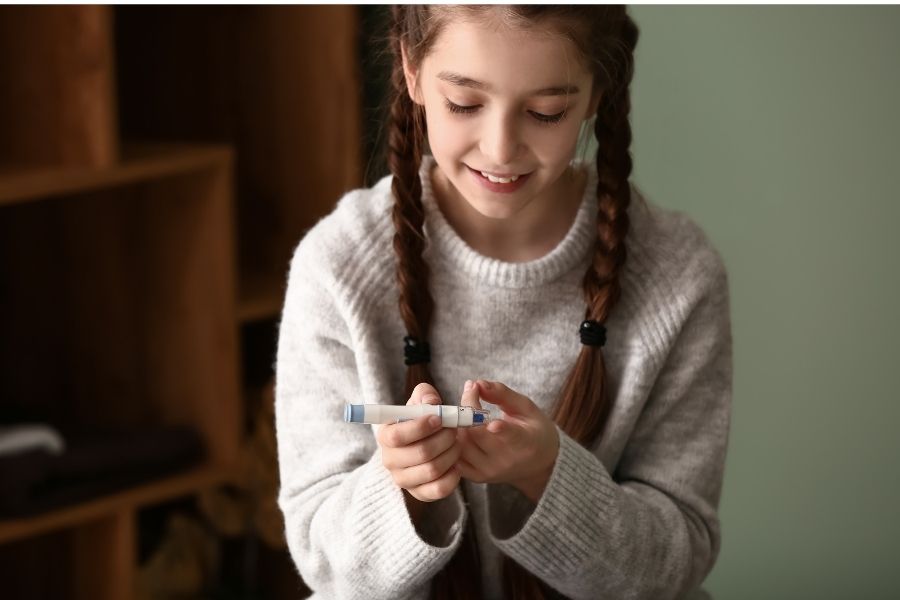 niña con trenzas pinchándose insulina