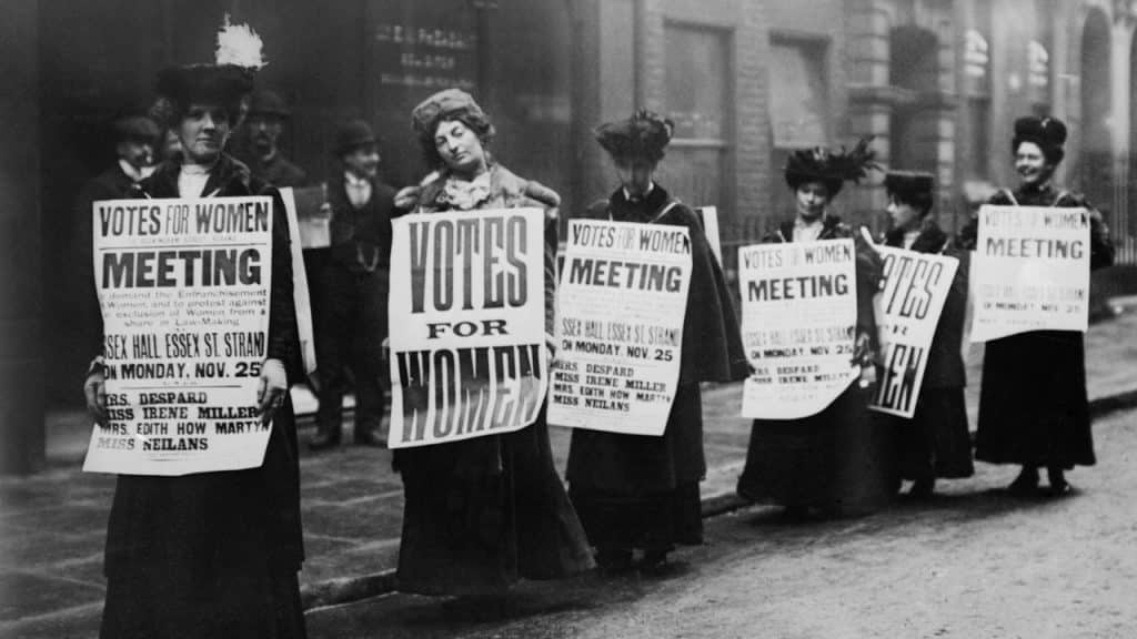 fotografía antigua en blanco y negro de mujeres portando pancartas para pedir el voto femenino